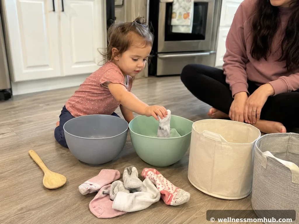 Kitchen-floor sock transfer setup with bowls, socks, and a wooden spoon — activities with a 15 month old