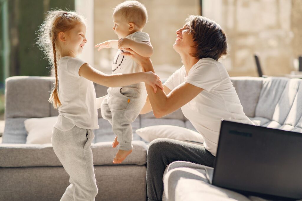 A mom playing with her two young kids in a bright living room