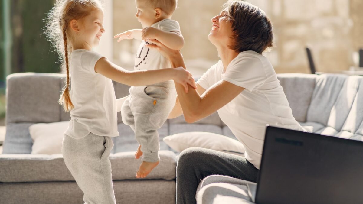 A mom playing with her two young kids in a bright living room