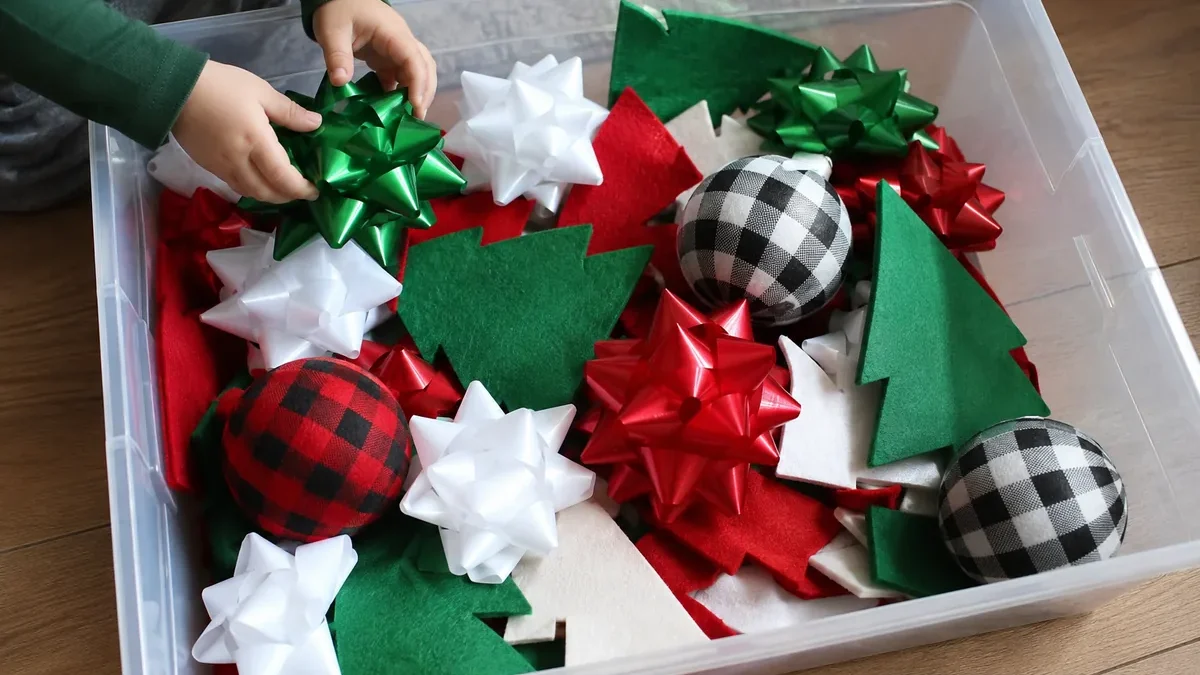 Christmas sensory bin ideas with gift bows, felt tree pieces, and shatterproof ornaments