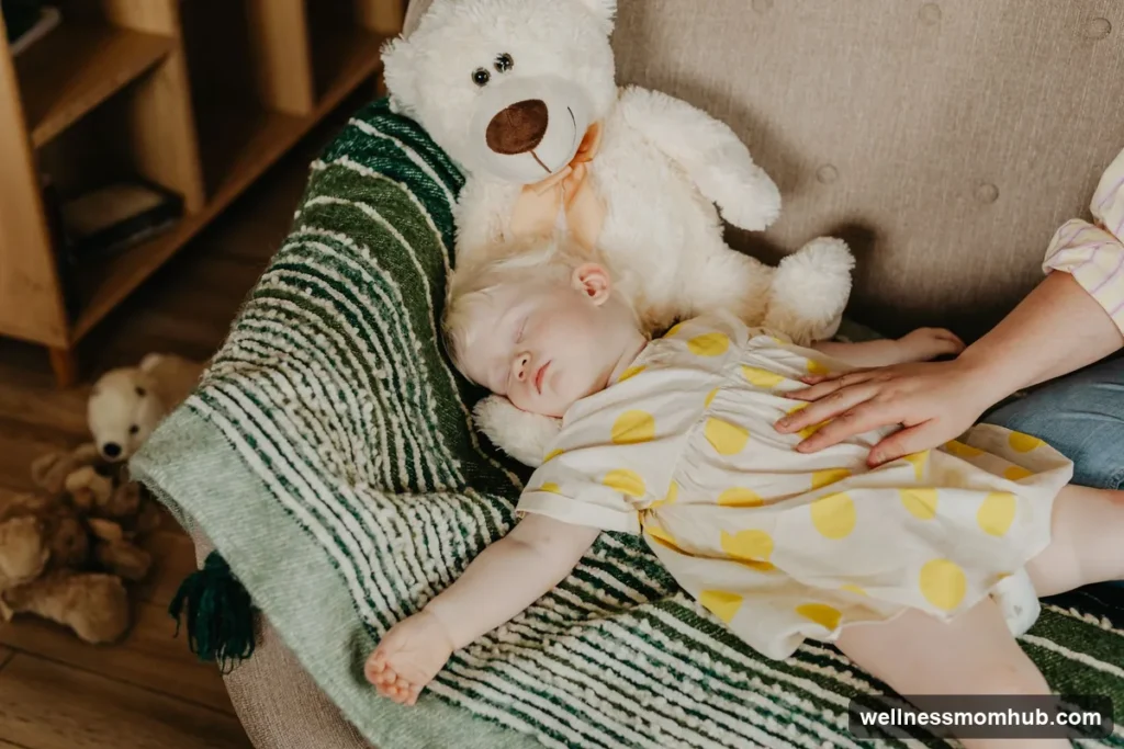 One-year-old napping on a blanket next to a teddy bear